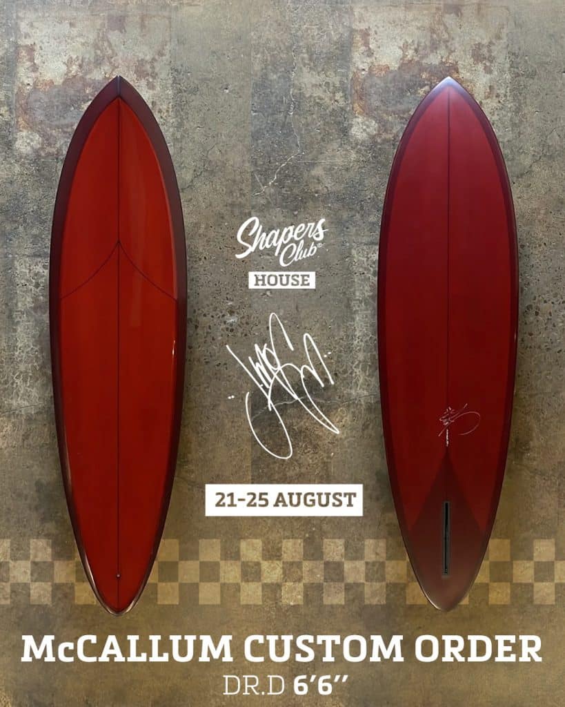 shapers-club- Une planche de surf rouge de Jeff McCallum est exposée de haut en bas sur un mur texturé. Le texte se lit comme suit : "Shapers Club House, 21-25 août, McCallum Custom Order, sur-mesure DR.D 6'6''" avec une signature au centre. -surf